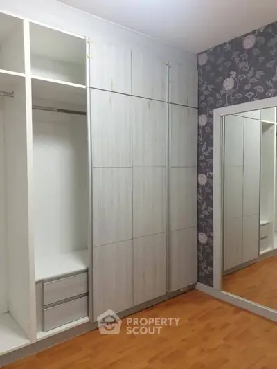 Spacious bedroom with built-in wardrobe and elegant floral wallpaper