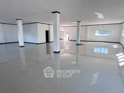 Spacious open-plan interior with glossy tiled floors and ample natural light, ideal for versatile use.