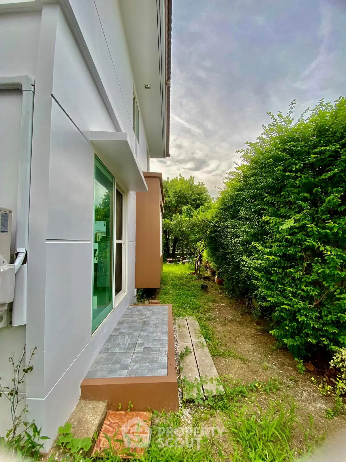 Charming side view of modern home with lush garden and patio area