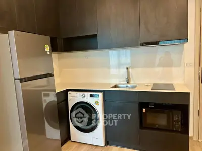 Modern kitchen with sleek appliances including fridge, washing machine, and microwave.