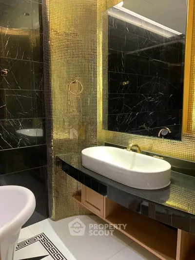 Luxurious bathroom with elegant black and gold accents, featuring a modern sink and stylish bathtub.