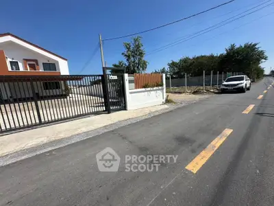 Modern house with gated entrance and driveway on a sunny day, showcasing suburban living.
