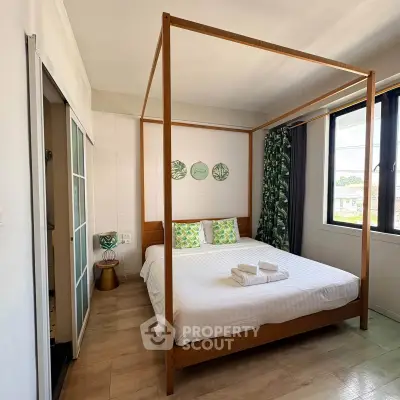 Charming bedroom with canopy bed and large window offering natural light and cozy ambiance.
