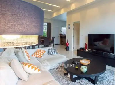 Spacious modern living room with cozy sectional sofa and large flat-screen TV, perfect for relaxation.