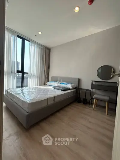Modern bedroom with large window and stylish furniture in a high-rise apartment.