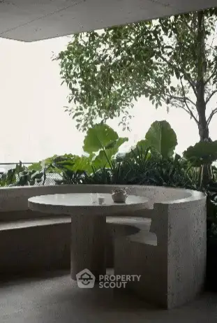 Stylish outdoor seating area with modern stone table and lush greenery