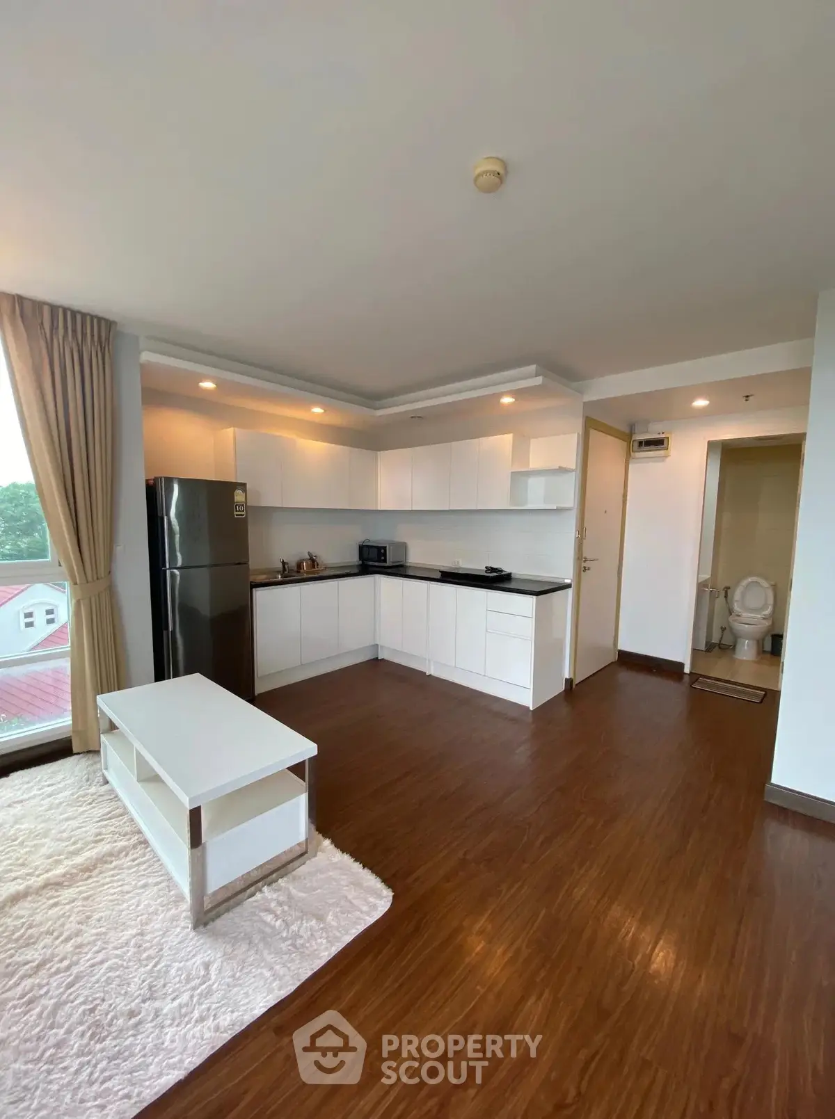 Spacious open-layout kitchen with modern appliances and cozy living area, featuring hardwood floors and natural light.