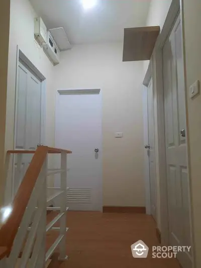 Modern hallway with wooden flooring and white doors in a stylish home interior.