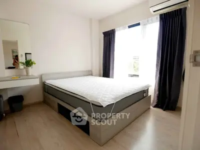 Modern bedroom with large window, stylish bed, and sleek wooden flooring in a bright apartment.