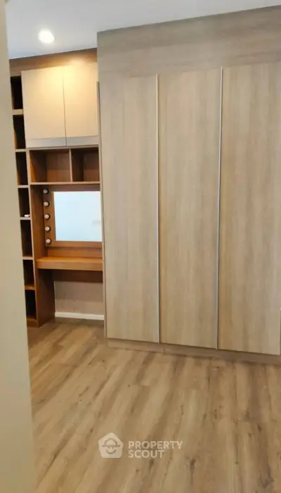 Spacious bedroom with modern wooden wardrobe and built-in vanity