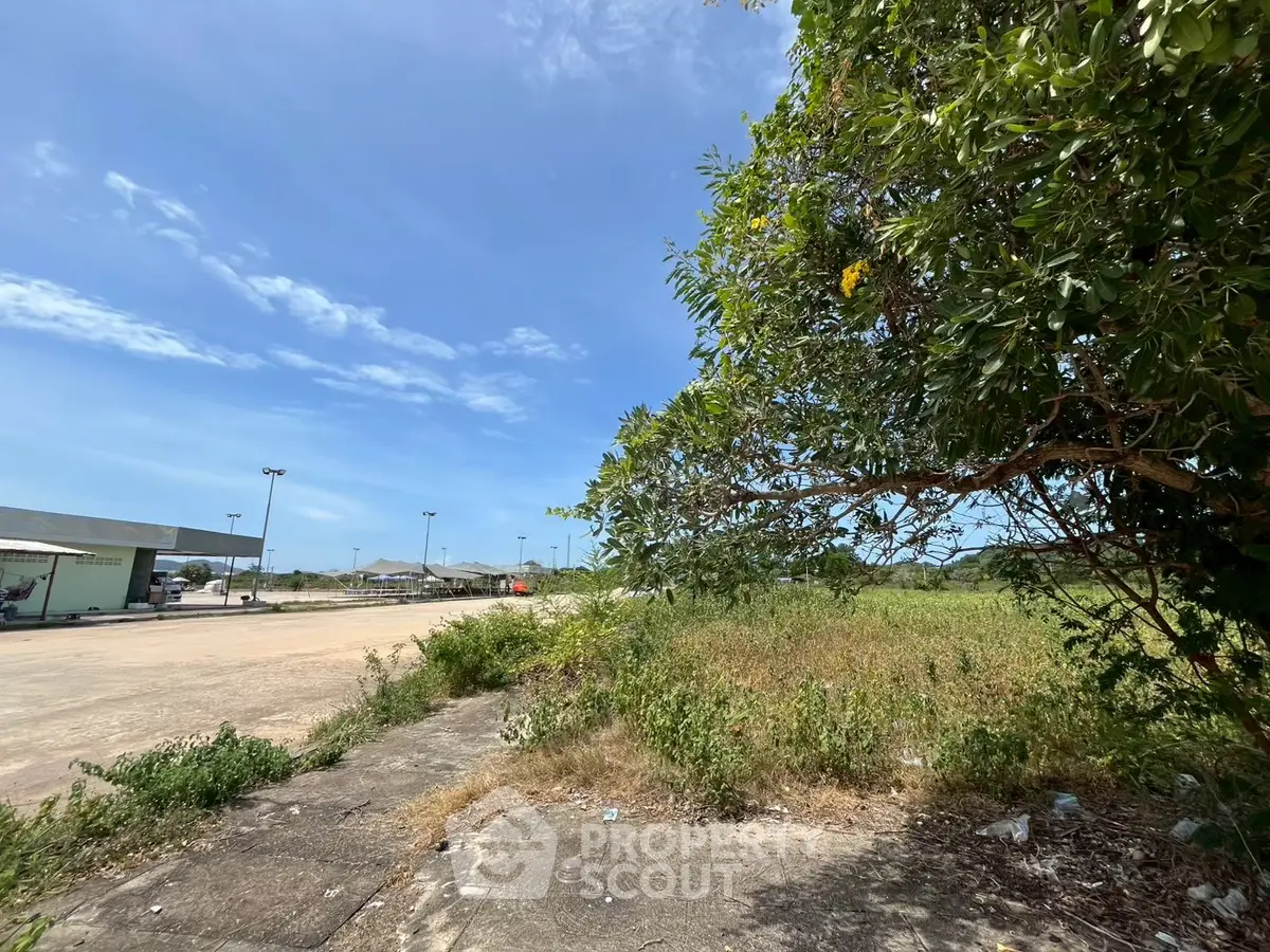 Expansive vacant land with lush greenery and clear blue sky, ideal for development opportunities.