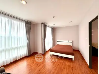 Spacious bedroom with large windows and wooden flooring in modern apartment