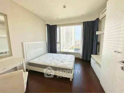 Spacious bedroom with large window offering city views, featuring a comfortable bed and elegant furnishings.