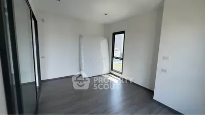 Spacious empty room with large window and wooden flooring, perfect for customization.