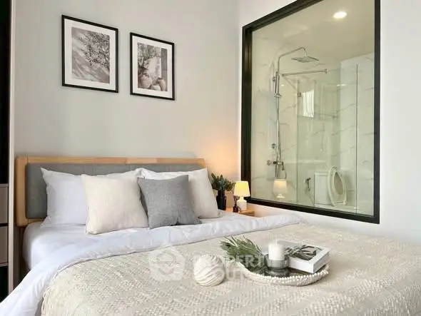 Modern bedroom with ensuite bathroom featuring glass partition and elegant decor.