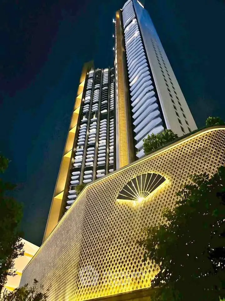 Stunning night view of a modern high-rise building with unique architectural design and illuminated facade.