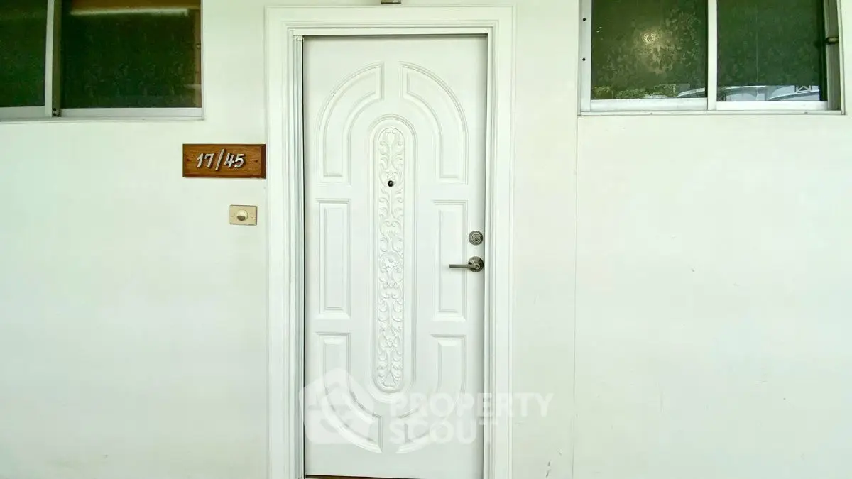 Elegant white entrance door with intricate design in modern apartment building.