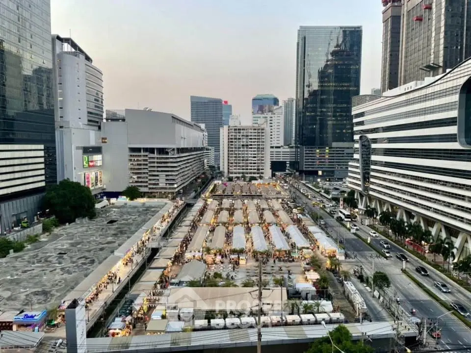 Aerial view of bustling cityscape with modern skyscrapers and vibrant street market.
