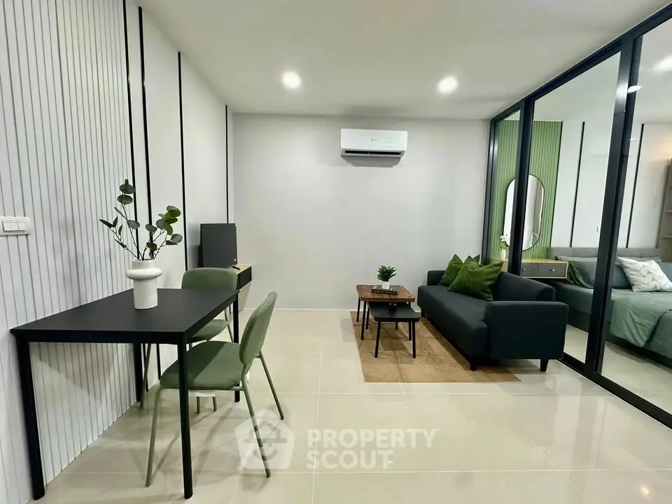Modern living room with sleek furniture and glass partition leading to bedroom