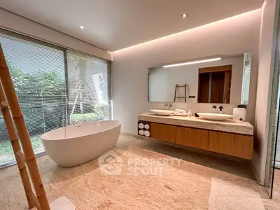 Luxurious bathroom with freestanding bathtub and modern double vanity in a serene setting.