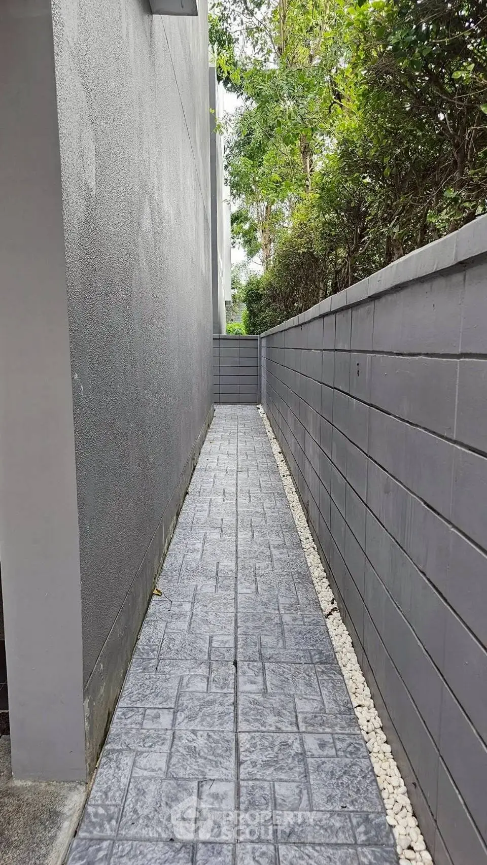 Narrow outdoor pathway with modern gray walls and stone flooring
