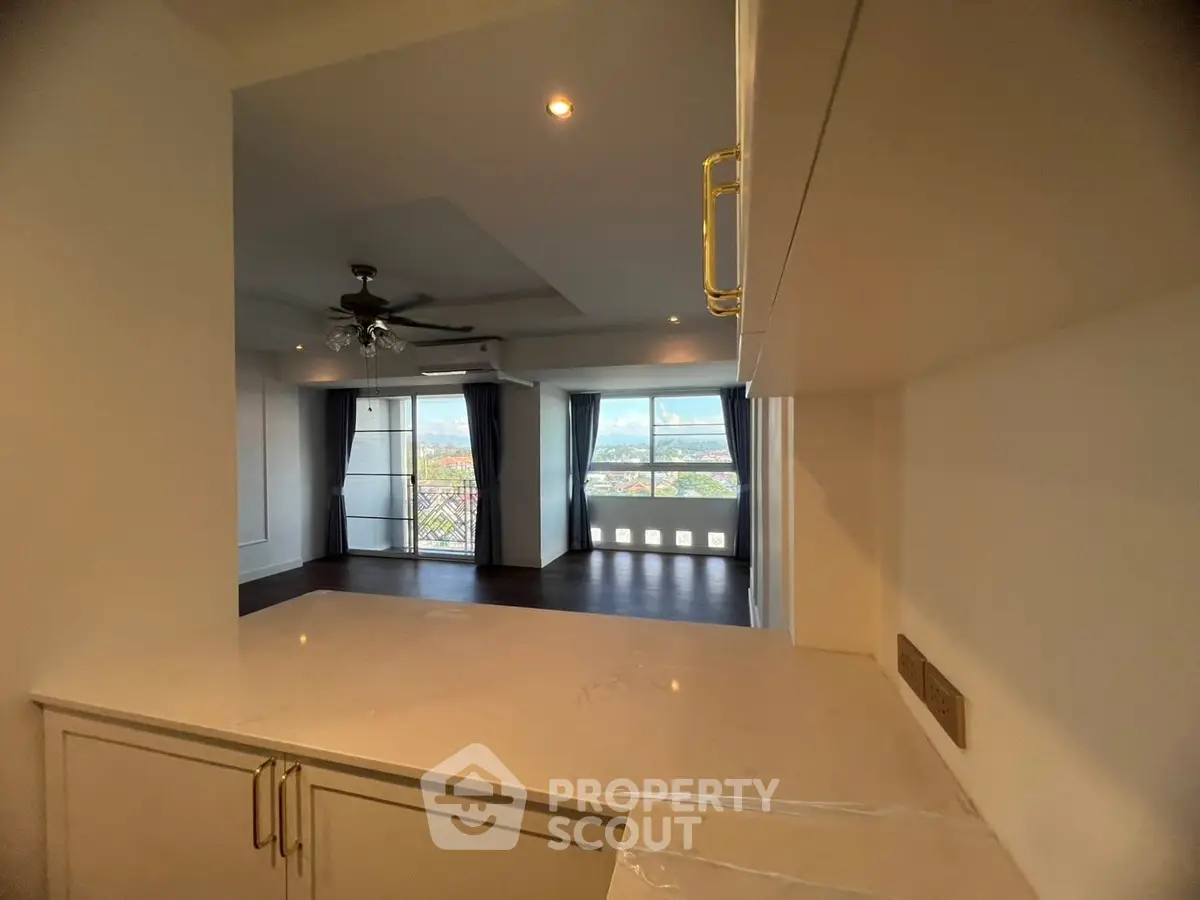 Spacious living room with large windows and modern ceiling fan, offering a bright and airy atmosphere.