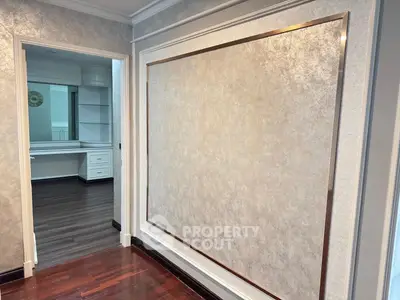 Elegant interior hallway with luxurious wall paneling and view into a study room with built-in shelves.