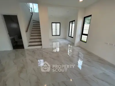 Spacious modern living room with glossy marble flooring and large windows.
