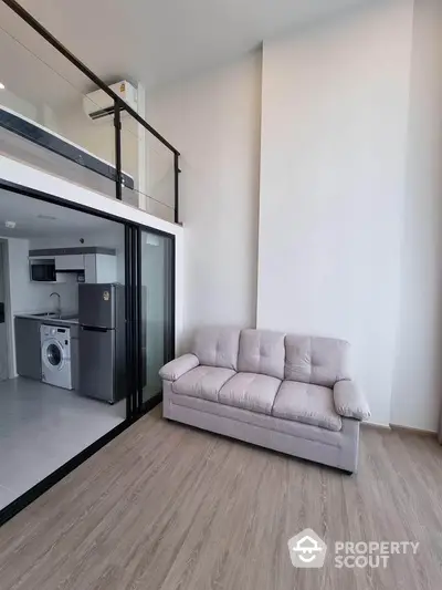 Modern loft apartment with mezzanine, featuring sleek kitchen and cozy living area.