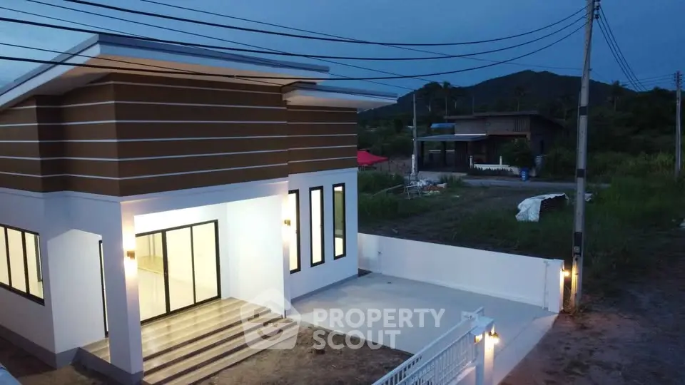 Modern single-story house with sleek design and spacious entrance at dusk.