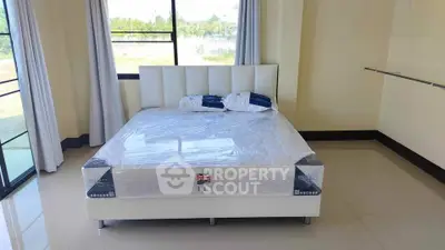 Spacious bedroom with large windows and modern bed in a bright, airy setting.