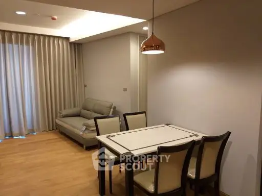 Modern living room with dining area, featuring stylish furniture and warm lighting.