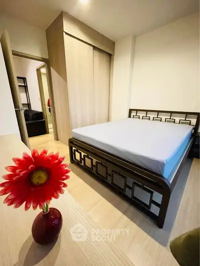 Modern bedroom with stylish bed and built-in wardrobe, featuring a vibrant flower decoration.