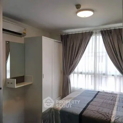 Cozy bedroom with natural light, featuring a bed, wardrobe, and air conditioning for comfort.