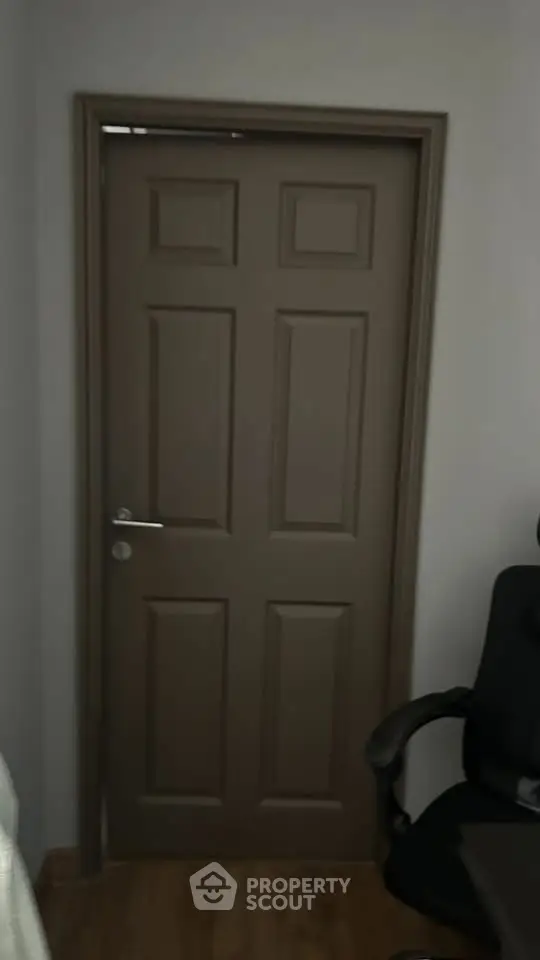 Interior view of a room with a closed wooden door and office chair, showcasing simple design.