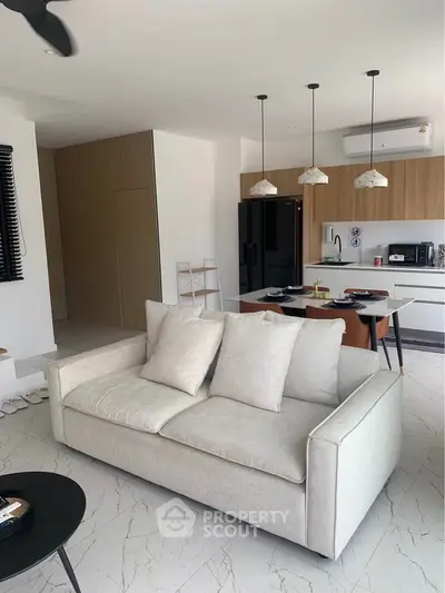 Modern open-plan living room and kitchen with sleek furniture and appliances.
