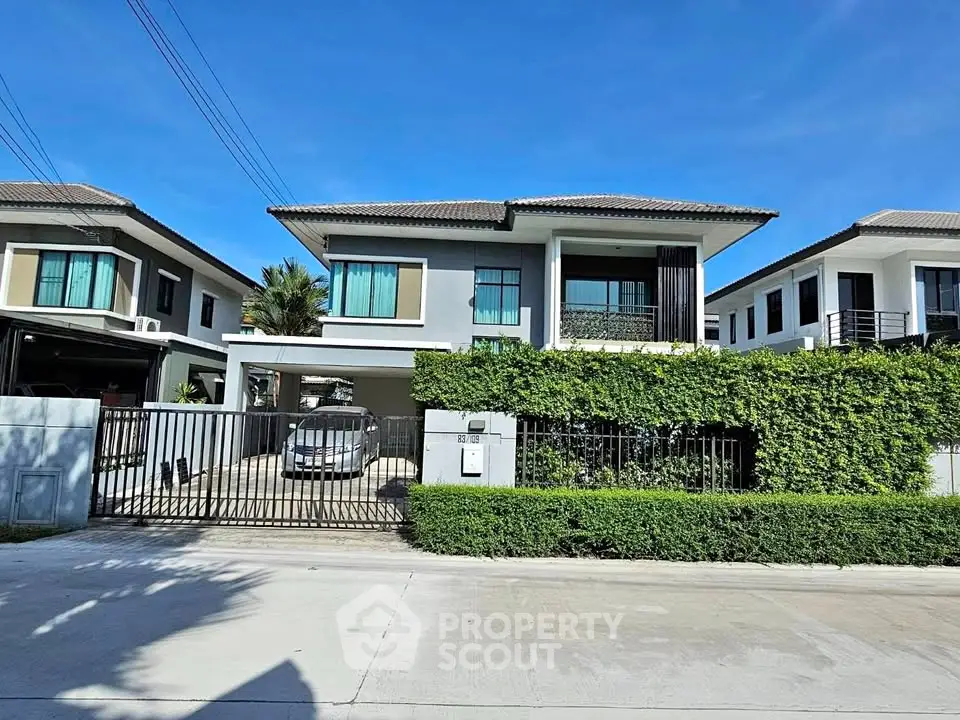 Modern two-story house with lush greenery and gated driveway