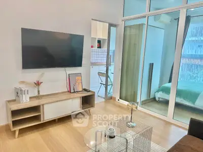 Modern living room with TV, stylish furniture, and glass doors leading to a cozy bedroom.