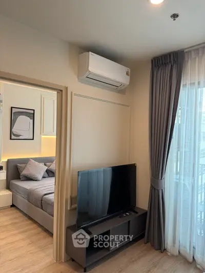 Modern living room with TV and air conditioning, adjacent to a cozy bedroom.