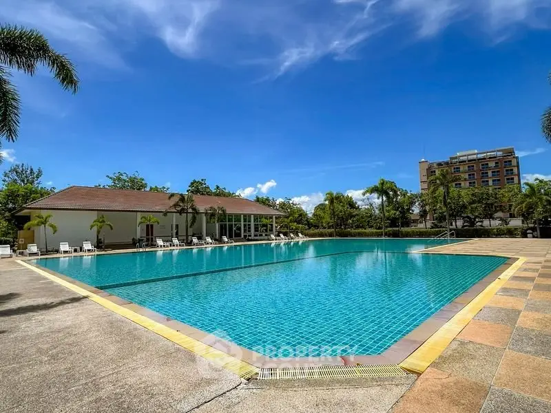 Luxurious outdoor pool area with clear blue water and palm trees, perfect for relaxation and leisure.