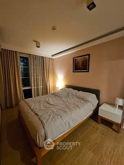 Cozy bedroom with modern decor and ambient lighting, featuring a large bed and elegant curtains.
