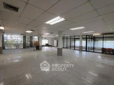 Spacious open-plan office space with large windows and modern lighting.