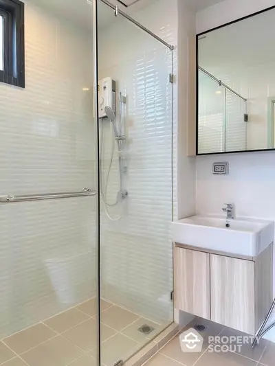 Modern bathroom with glass shower and sleek vanity in contemporary home.