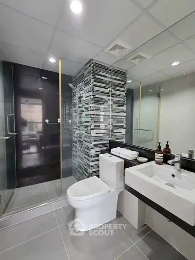 Modern bathroom with glass shower and sleek fixtures in contemporary apartment.