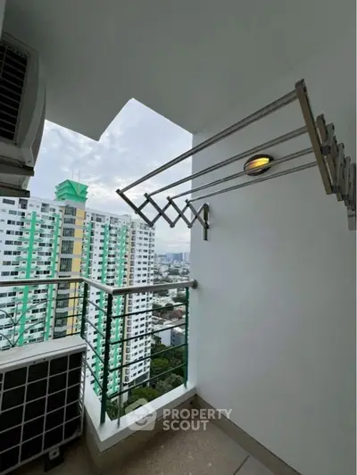 Modern balcony with city view and laundry rack in high-rise apartment