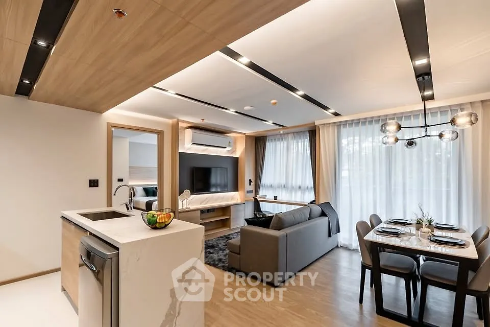 Modern open-plan living room with stylish kitchen and dining area, featuring elegant lighting and contemporary decor.