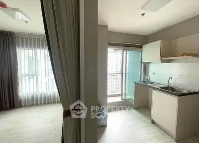 Modern apartment interior with open kitchen and balcony view, featuring sleek cabinetry and natural light.
