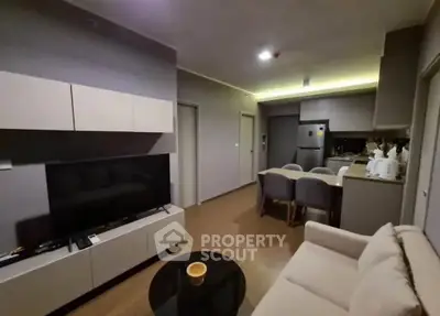 Modern living room with open kitchen, sleek furniture, and cozy ambiance.