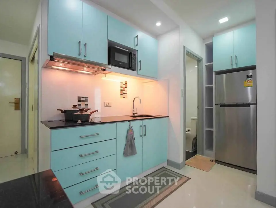 Modern kitchen with sleek blue cabinets and stainless steel appliances in a stylish apartment.