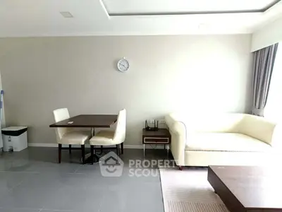 Modern living room with elegant white sofa and dining area, featuring sleek tile flooring and natural light.